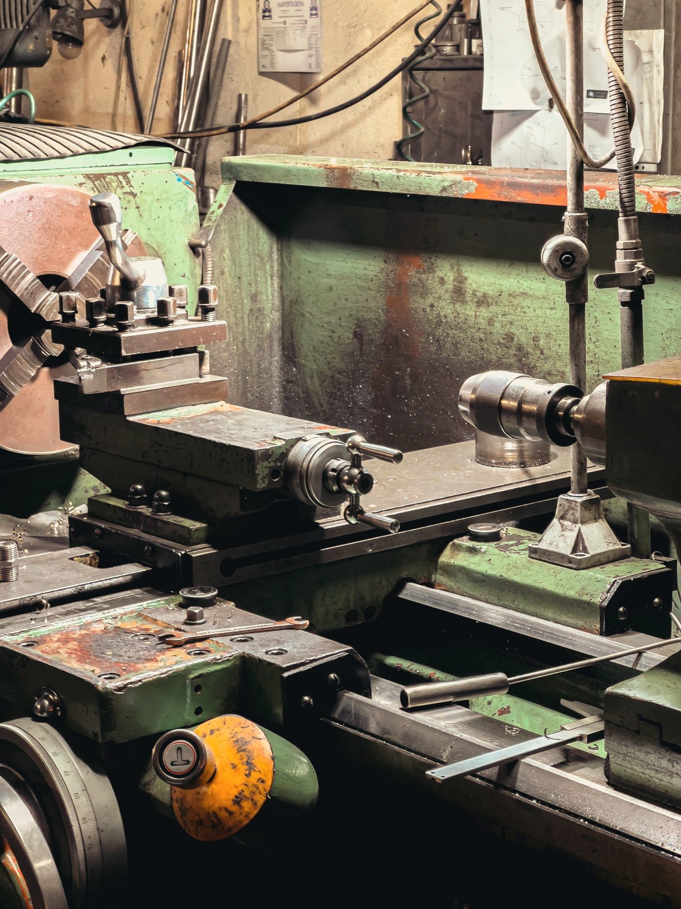 A metal lathe bed with chuck and tool post in a workshop