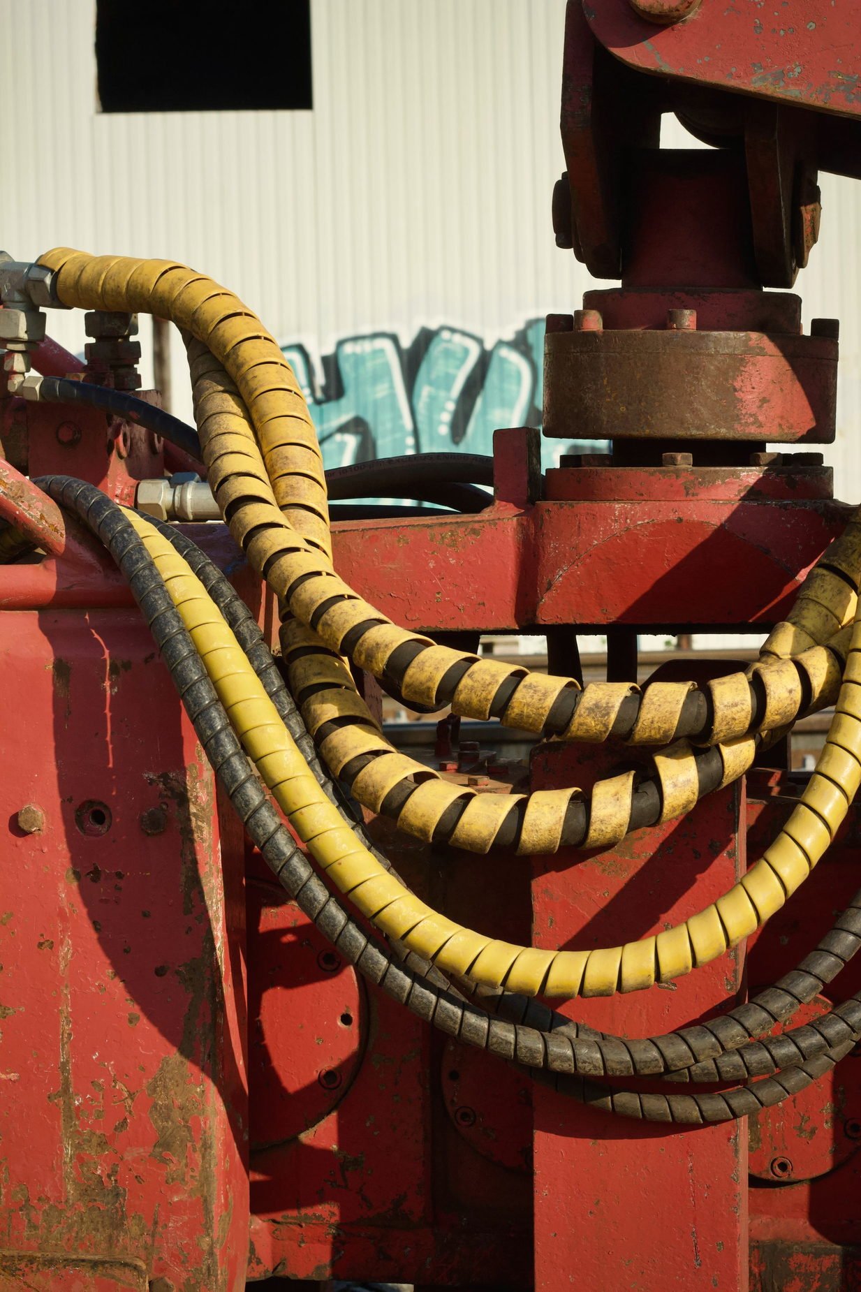 Spiral wrapped hydraulic hoses running along red machinery