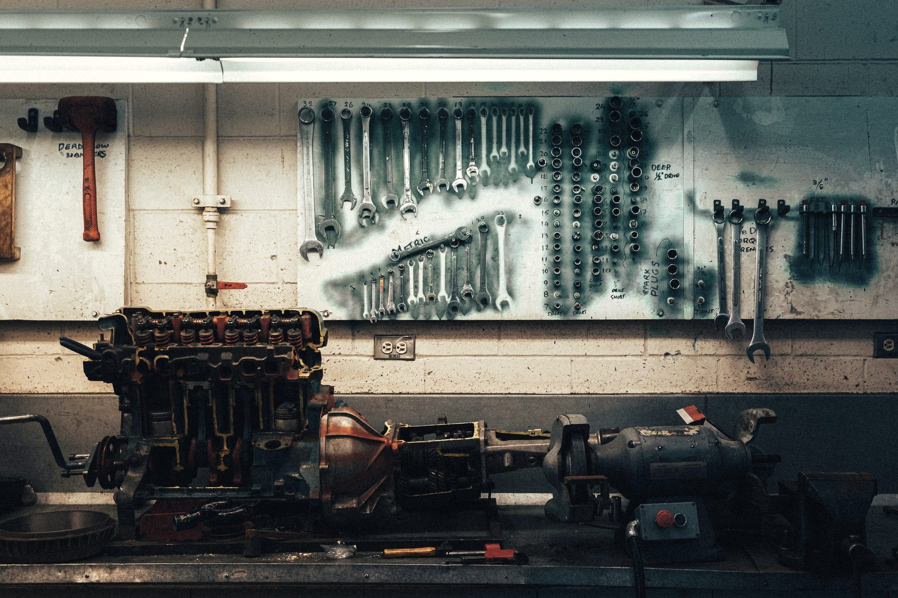 A wall rack of wrenches above a workshop bench